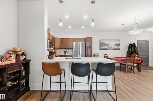 Kitchen featuring a peninsula with countertop seating, wood-finish flooring, stainless steel appliances, and recessed lighting - 217 2503 Hanna Crescent, Edmonton, AB 