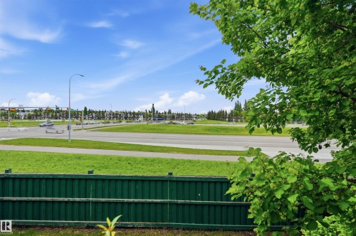 Green picket fence bordering a grassy area with mature trees - 217 2503 Hanna Crescent, Edmonton, AB 