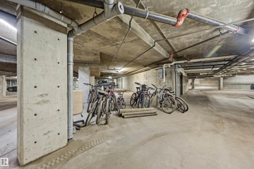 Underground parking area featuring exposed concrete structural elements and overhead utility piping - 217 2503 Hanna Crescent, Edmonton, AB 