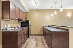 Kitchenette featuring wood-finish flooring, dark wood cabinetry, and speckled countertops - 