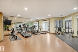 Dedicated fitness area featuring a mirrored wall, recessed lighting, and large windows - 