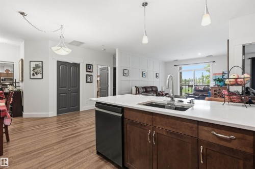 Kitchen island featuring a single-basin sink with a gooseneck faucet, integrated dishwasher, and rich wood-finish cabinetry - 217 2503 Hanna Crescent, Edmonton, AB 