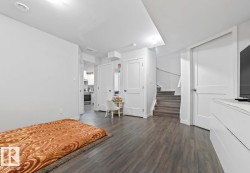 Spacious interior room featuring wood-finish flooring, recessed lighting, and crisp white walls - 