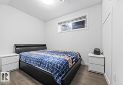 Bedroom featuring wood-finish flooring, white walls, and a recessed window - 