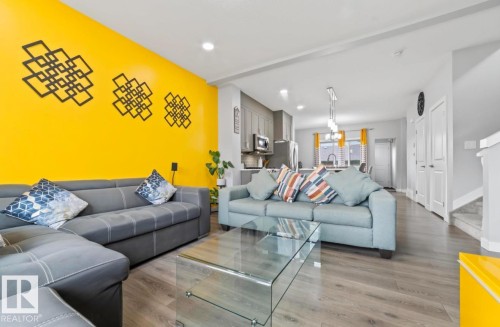 Open-concept living space featuring wood-finish flooring, recessed lighting, and a brightly painted accent wall - 2153 Maple Road, Edmonton, AB 