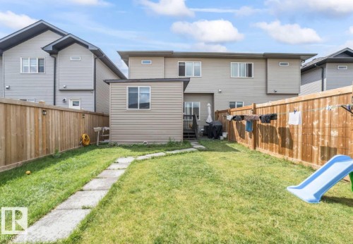 Expansive green space featuring a concrete paver pathway, a private wooden fence, and a detached shed with siding - 2153 Maple Road, Edmonton, AB 