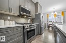 Contemporary kitchen featuring gray cabinetry, stainless steel appliances, white countertops, and a gray subway tile backsplash - 2153 Maple Road, Edmonton, AB 