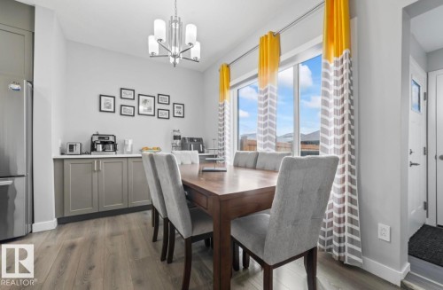 Dining area with wood-finish flooring, a contemporary chandelier, and a built-in buffet with light gray cabinetry and a white countertop - 2153 Maple Road, Edmonton, AB 
