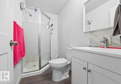Bathroom featuring a glass-enclosed shower, white vanity with integrated sink, contemporary faucet, and wood-finish flooring - 
