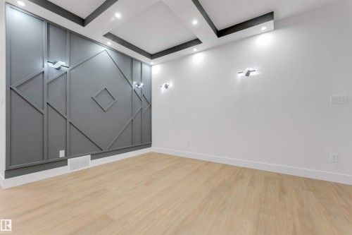 Room featuring a decorative accent wall with geometric molding, recessed ceiling lighting, and light wood-finish flooring - 131 24 Street, Edmonton, AB 