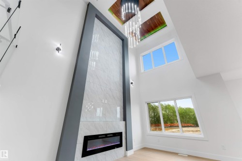 Soaring ceilings with an integrated linear fireplace set into a large format tile surround - 131 24 Street, Edmonton, AB 