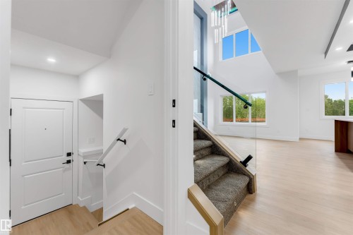 Entryway featuring light wood-finish flooring and a white paneled door with black hardware - 131 24 Street, Edmonton, AB 