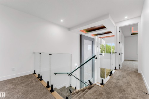 Upper-level landing featuring glass railings with matte black hardware, recessed ceiling lighting, and wood-finish flooring accents - 131 24 Street, Edmonton, AB 