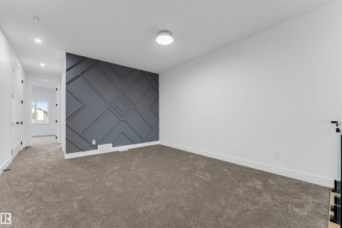 Accent wall with geometric paneling, plush carpet flooring, white baseboards, and a contemporary ceiling light fixture - 131 24 Street, Edmonton, AB 