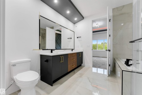 Dual vanity with stone countertop and integrated sinks, matte black fixtures, and a large frameless mirror with gold accents - 131 24 Street, Edmonton, AB 