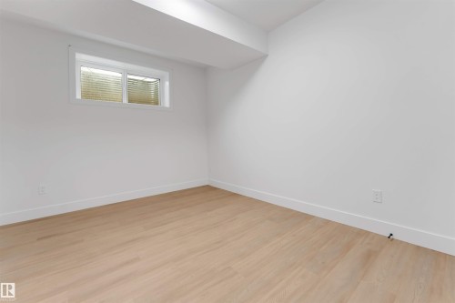 Bright room featuring light wood-finish flooring, white walls, and a single window with blinds - 131 24 Street, Edmonton, AB 