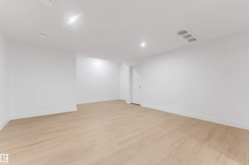 Spacious room featuring light wood-finish flooring, white walls, and recessed lighting - 131 24 Street, Edmonton, AB 