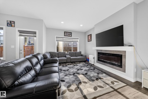 Living area featuring a modern linear electric fireplace with a stone-look surround, recessed lighting, wood-finish flooring, and light gray wall paint - 2084 Graydon Hill, Edmonton, AB 