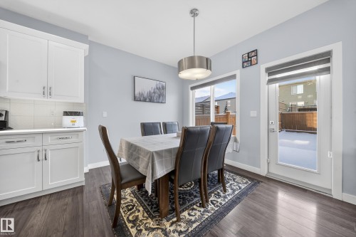 Dining area featuring wood-finish flooring, white cabinetry, a built-in countertop, a contemporary pendant light fixture, and a glass-paneled exterior door - 2084 Graydon Hill, Edmonton, AB 