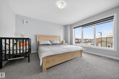 Light-filled bedroom featuring expansive windows with roller shades, light gray wall finishes, and gray carpeting - 2084 Graydon Hill, Edmonton, AB 