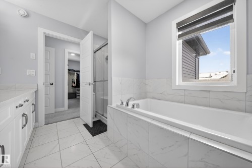 Bathroom featuring a built-in soaking tub, tiled surround, and white vanity with stone countertop - 2084 Graydon Hill, Edmonton, AB 