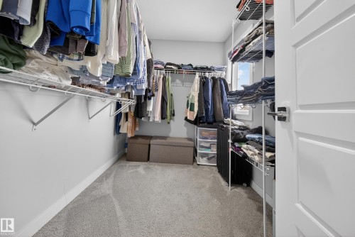 Spacious walk-in closet featuring light gray walls, gray carpet flooring, and white trim - 2084 Graydon Hill, Edmonton, AB 