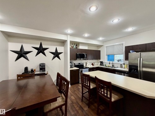 Open-concept kitchen and dining area featuring rich wood-finish flooring - 45 6075 Schonsee Way, Edmonton, AB 