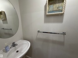 Pedestal sink with chrome faucet, complemented by a large circular frameless mirror - 
