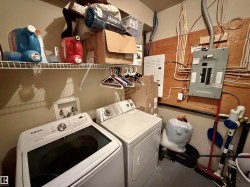 Dedicated laundry area featuring a washer and dryer hookup, overhead wire shelving, and a visible electrical panel - 