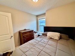 Neutral-toned bedroom featuring a single window with white trim, a wood-finish door, and textured ceiling - 