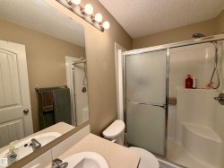 Three-light vanity fixture above a large mirror and a shower with frosted sliding glass doors - 