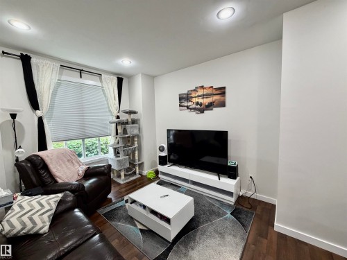 Living area featuring wood-finish flooring, recessed lighting, and a window with blinds and curtain rods - 45 6075 Schonsee Way, Edmonton, AB 