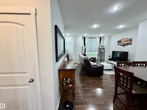 Open-concept living area featuring wood-finish flooring, recessed lighting, and white trim throughout - 45 6075 Schonsee Way, Edmonton, AB 