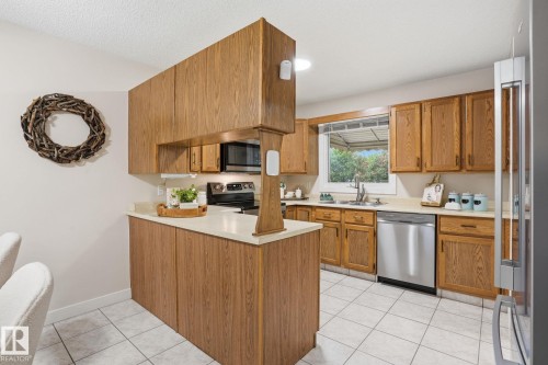 Kitchen featuring wood-finish cabinetry, stainless steel dishwasher, and built-in microwave - 1008 61 Street, Edmonton, AB 