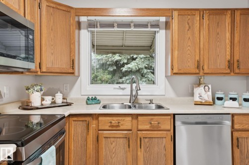 Kitchen featuring wood cabinetry with brass hardware, a stainless steel double basin sink with a high-arc faucet, and light-toned countertops - 1008 61 Street, Edmonton, AB 