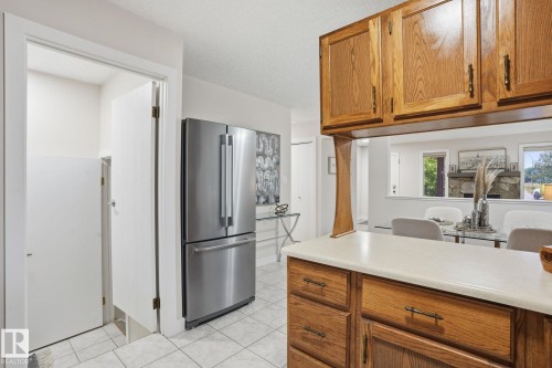Kitchen featuring wood cabinetry, light countertops, and a stainless steel refrigerator - 1008 61 Street, Edmonton, AB 