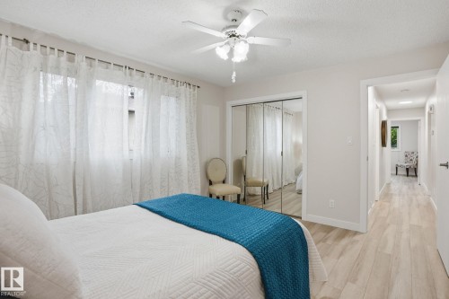 Bedroom featuring wood-finish flooring, a ceiling fan with integrated lighting, and a mirrored sliding closet door - 1008 61 Street, Edmonton, AB 