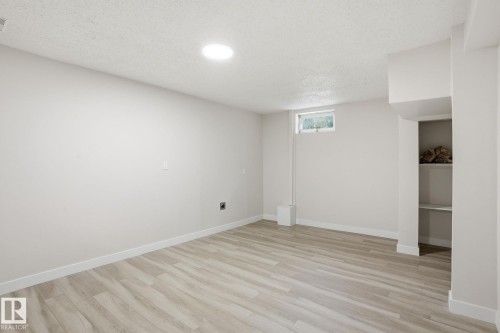 Spacious room featuring wood-finish flooring, recessed lighting, and a neutral color palette - 1008 61 Street, Edmonton, AB 