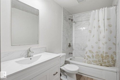 Bathroom featuring a white vanity with an integrated sink, brushed nickel faucet, and a large wall-mounted mirror - 1008 61 Street, Edmonton, AB 