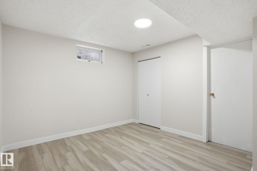Interior room featuring wood-finish flooring, white baseboards, and neutral wall paint - 1008 61 Street, Edmonton, AB 