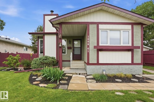 Two-tone exterior with contrasting trim, featuring a concrete walkway, established landscaping, and a fenced perimeter - 1008 61 Street, Edmonton, AB 