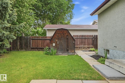 Expansive grass lawn featuring a wood storage shed, privacy fencing, and mature trees - 1008 61 Street, Edmonton, AB 