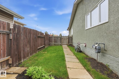 Side yard with concrete paver pathway, green lawn, and wood privacy fencing - 1008 61 Street, Edmonton, AB 