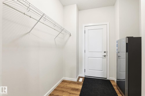 Entryway featuring wood-finish flooring, white baseboards, and a white two-panel door with brushed nickel hardware - 20011 26, Edmonton, AB 