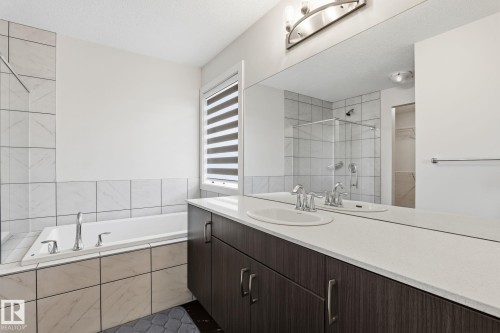 Bathroom featuring a dual vanity with a light-toned countertop, integrated sinks, and dark wood-finish cabinetry - 20011 26, Edmonton, AB 