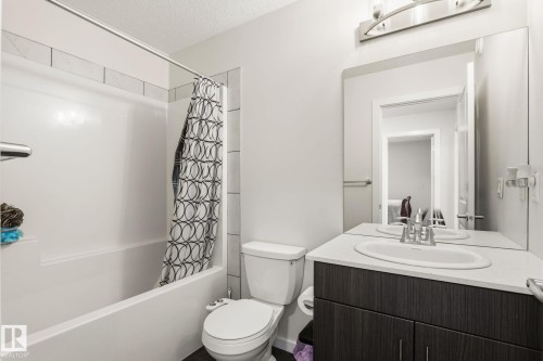 Full bathroom featuring a single vanity with dark wood-finish cabinetry, a white countertop, and an integrated sink - 20011 26, Edmonton, AB 