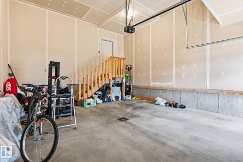 Concrete flooring in an unfinished garage with wood stairs and a garage door opener system - 20011 26, Edmonton, AB 
