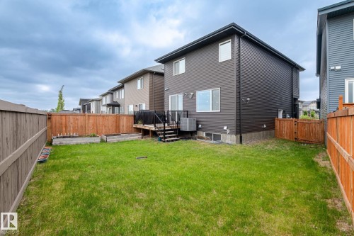 Expansive backyard featuring a manicured lawn, wood fencing, and a multi-level deck with black railings - 20011 26, Edmonton, AB 