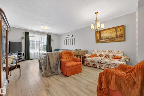 Spacious living area featuring light wood-finish flooring, a contemporary chandelier, recessed ceiling lighting, and crown molding - 85 165 Cy Becker Boulevard, Edmonton, AB - Indoor Photo Showing Living Room