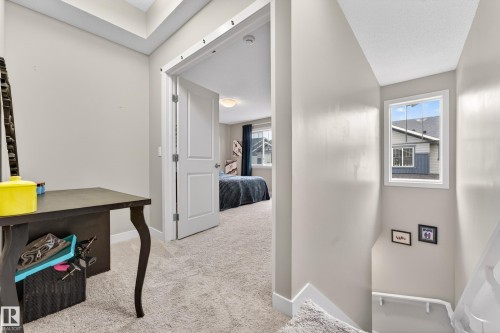 Carpeted hallway with a window and a doorway leading to an additional carpeted room with an additional window - 85 165 Cy Becker Boulevard, Edmonton, AB - Indoor Photo Showing Other Room